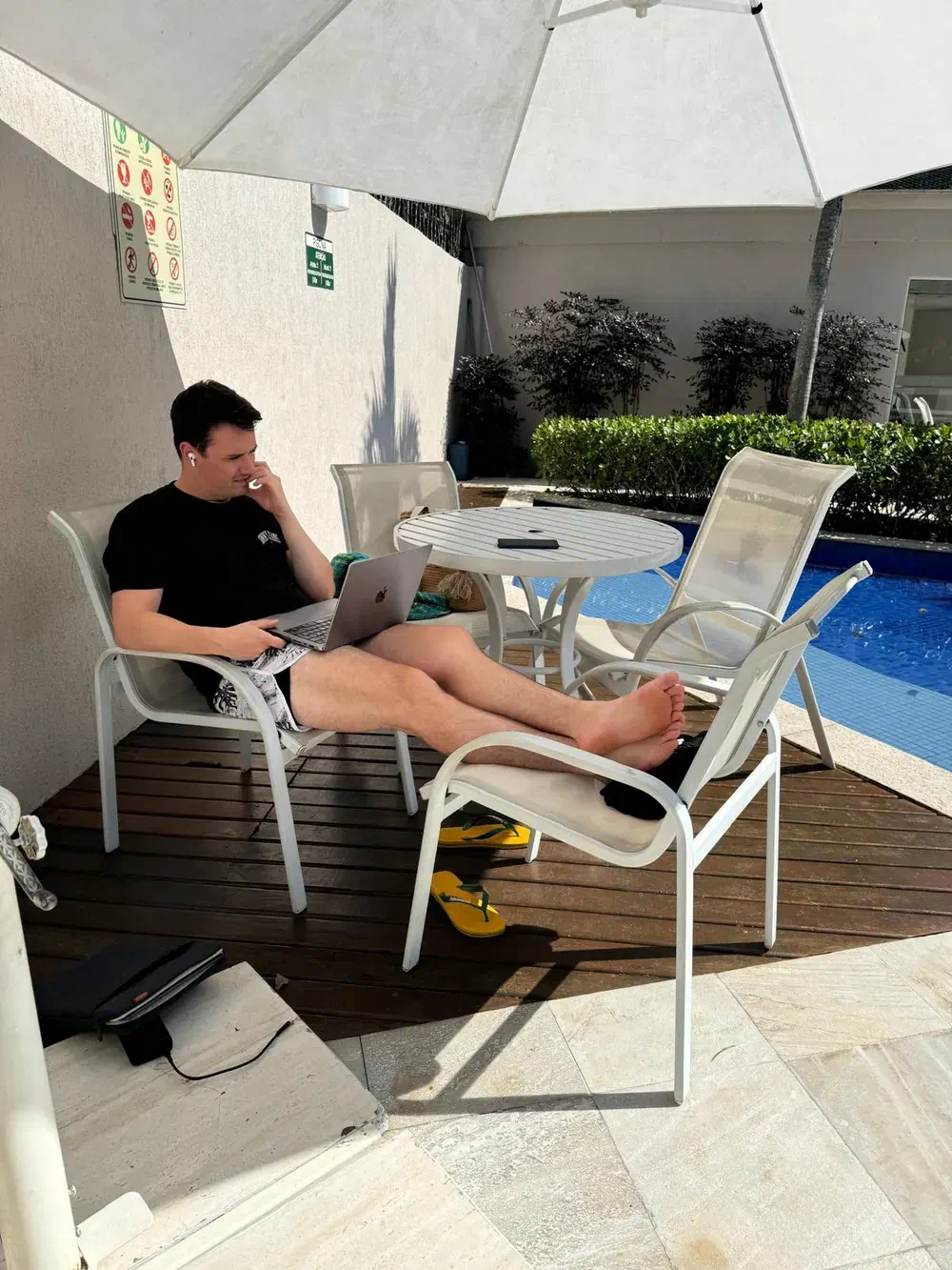 Christof Jori working on a laptop beside a swimming pool