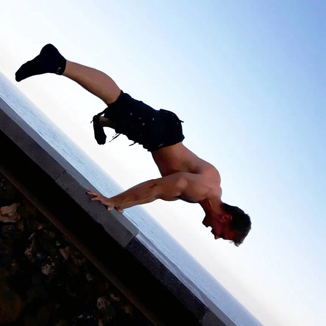 Kevin Riedl balancing in a calisthenics hold beside the sea Kevin Riedl balancing in a calisthenics hold beside the sea
